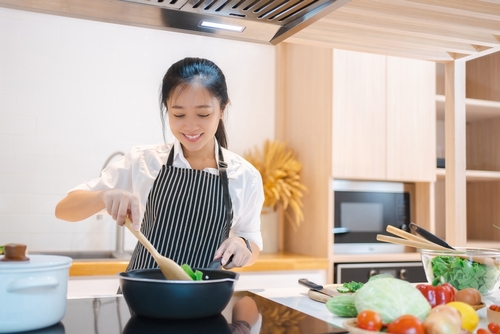 Cooking,Happy,Woman,Wear,Apron,In,Kitchen.,She,Is,Sautéing