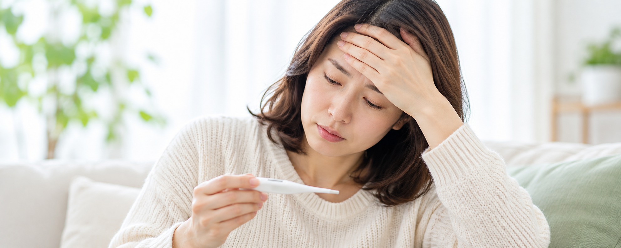 体温計を確認し、額に手を当てる女性のイメージ