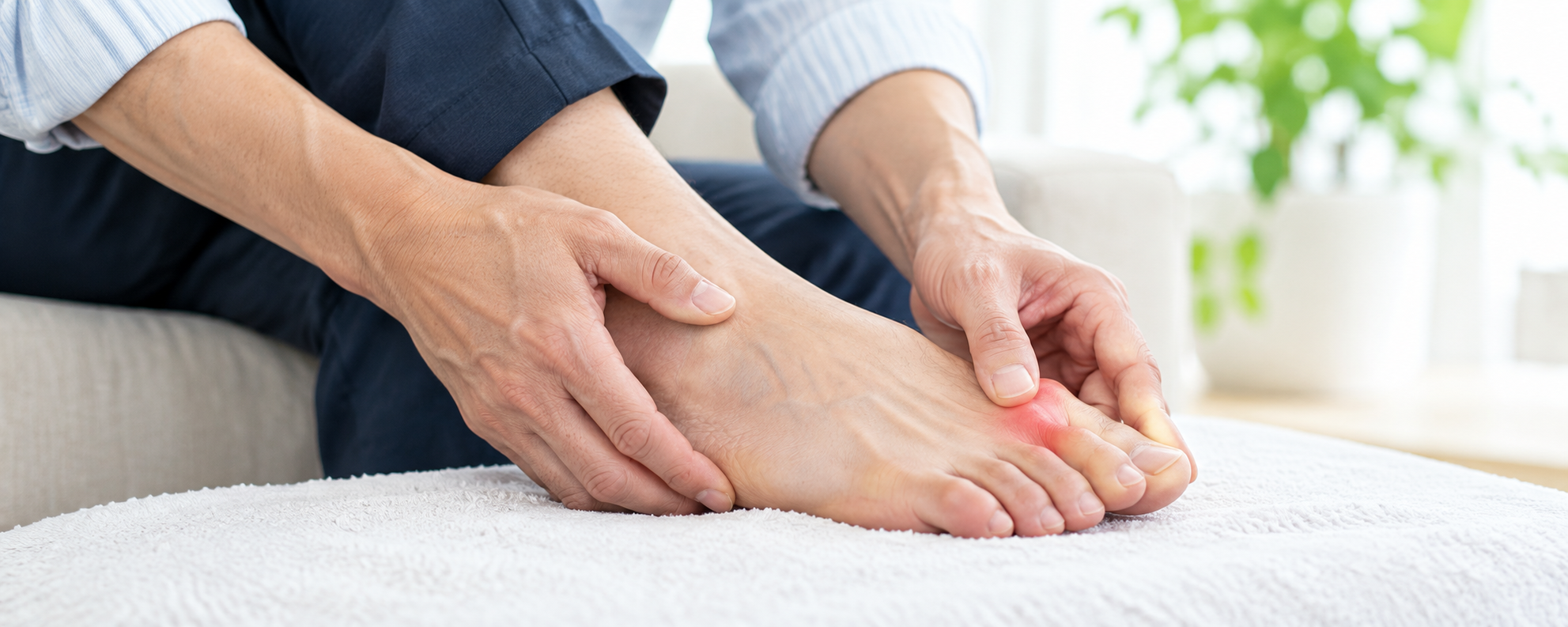 足の親指の付け根に手を添える男性のイメージ
